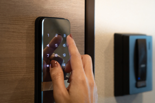 a woman's finger with maroon nail paint pressing the button 3 on an electronic security system